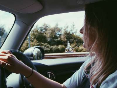 passenger shot of a women with blond hair driving car with one hand 
