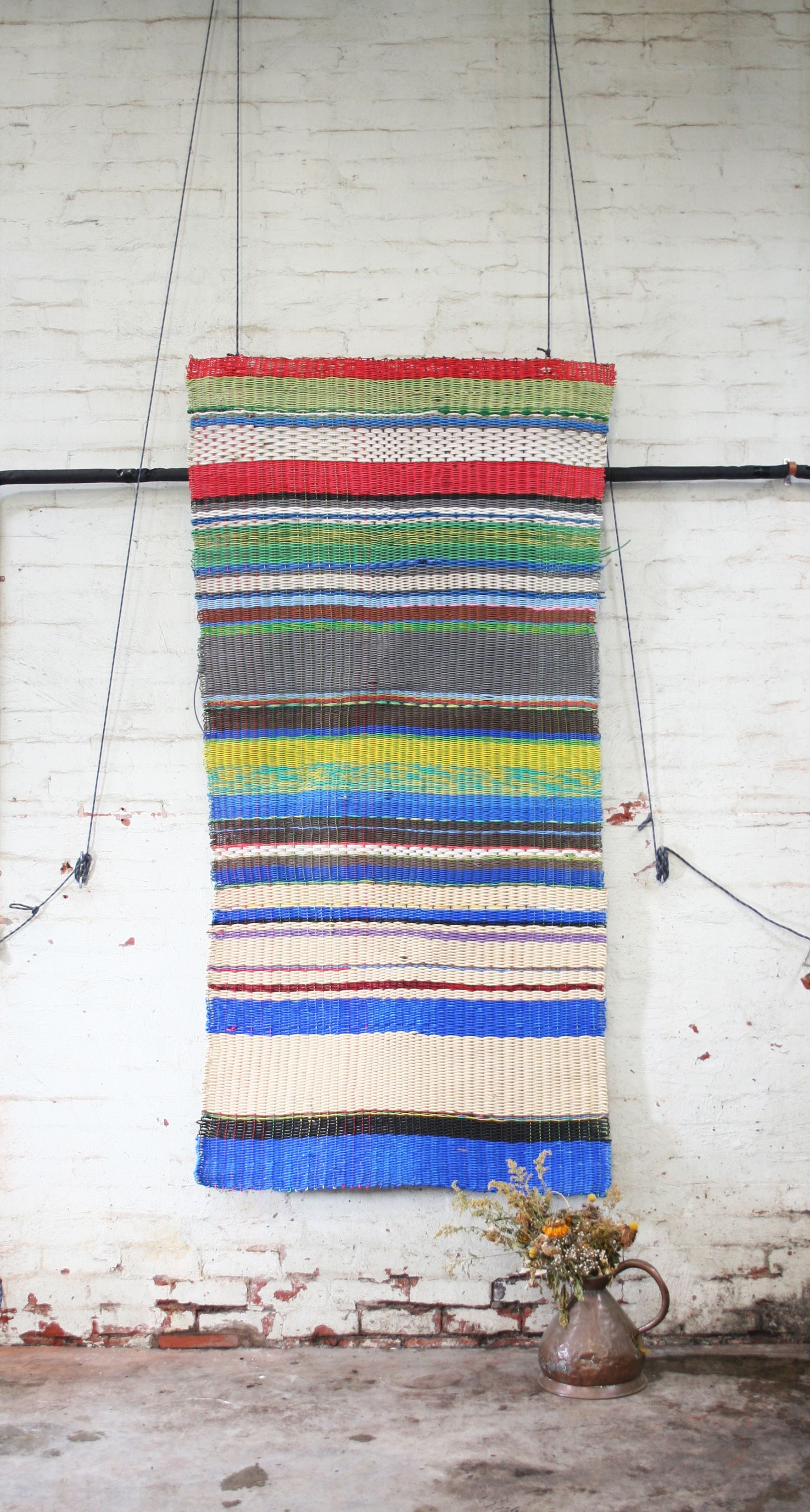 loom weave of electrical waste in blue, black, cream, red, yellow stripes