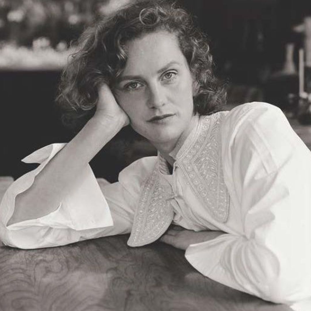 black and white photo of women with short curly hair staring into camera wearing a white shirt with a detailed collar.